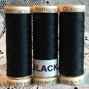 May include: Three spools of black Gutermann thread, each with a label that reads "BLACK" and "100 m - 110 yds".