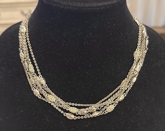 May include: A silver multi-strand necklace with small oval-shaped beads. Each bead is covered in tiny sparkling stones.