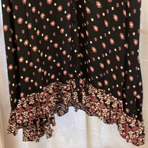 May include: A black maxi dress with a floral print and a ruffled hem. The dress has a button-up front and a relaxed fit.