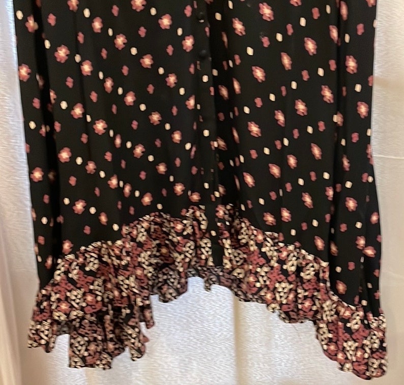 May include: A black maxi dress with a floral print and a ruffled hem. The dress has a button-up front and a relaxed fit.