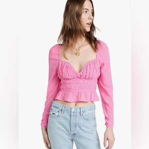 May include: A pink, long-sleeved, cropped top with a sweetheart neckline and a gathered waist.