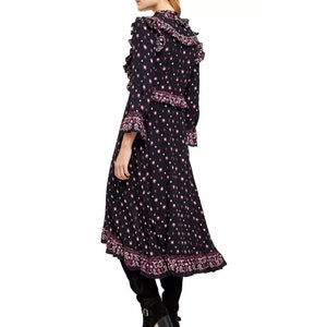 May include: A black midi dress with a pink and white floral print. The dress has a ruffled neckline and long sleeves. The dress has a high-low hemline.
