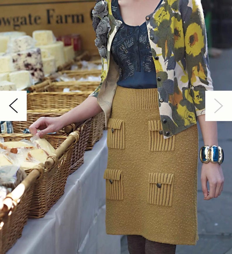 May include: A woman wearing a mustard yellow knitted skirt with multiple pockets and a floral cardigan. The skirt has a textured surface and the cardigan has a white background with yellow, green, and blue floral accents.