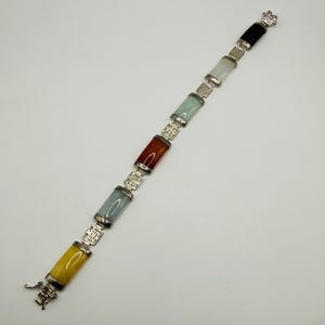 May include: A multi-colored bracelet featuring rectangular stone links in yellow, pale green, orange, light green, and black. The stones are connected by silver-toned metal links with intricate openwork designs and a secure metal clasp at the end.