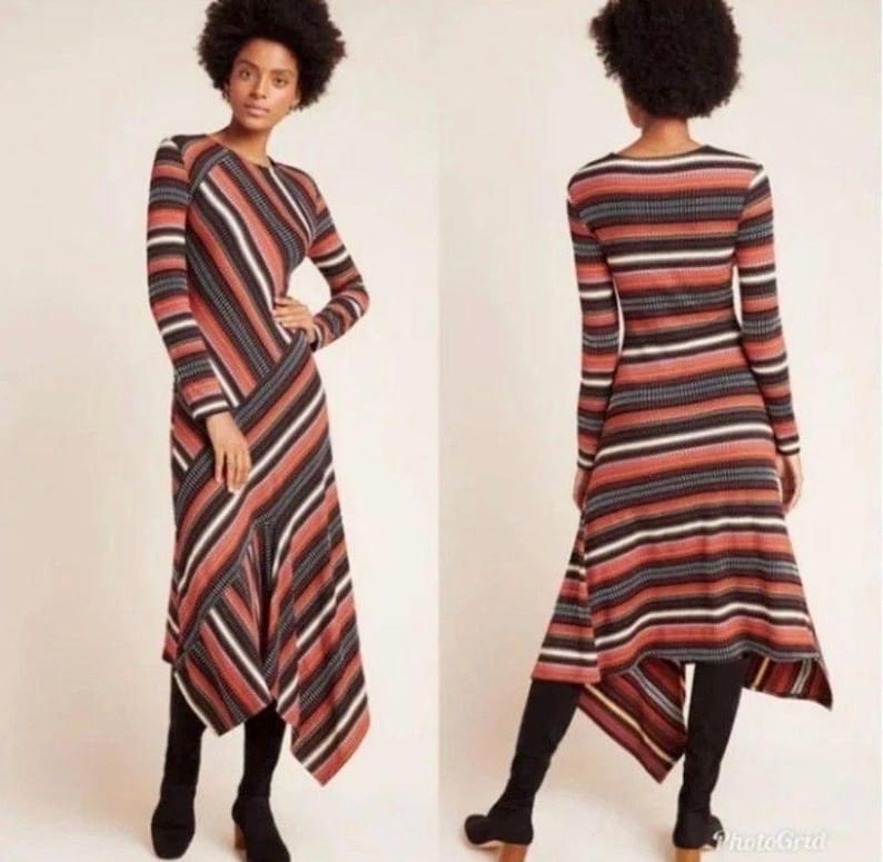 Puede incluir: Vestido de manga larga con estampado de rayas en tonos rojos, negros y blancos. El vestido tiene un dobladillo asim&eacute;trico y se combina con botas negras. La imagen muestra el vestido por delante y por detr&aacute;s.