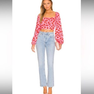 K&ouml;nnte beinhalten: Ein rosa-rotes, blumiges Crop-Top mit langen &Auml;rmeln, quadratischem Ausschnitt und figurbetonter Silhouette. Das Top wird mit einer hellblauen, hoch sitzenden Jeans kombiniert.