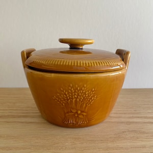 May include: A brown ceramic covered dish with a wheat design. The lid has a knob on top.