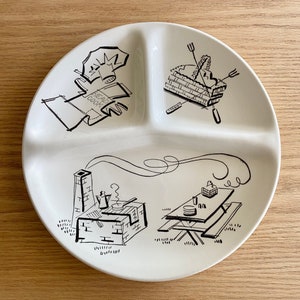 May include: A white ceramic divided serving plate with black line drawings of a campfire, a picnic table, and a tent. The plate is divided into three sections.