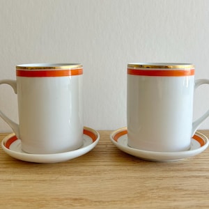 Juego de 2 tazas y platillos de porcelana blanca con detalles en naranja y dorado de Lagardo Tackett para Schmid