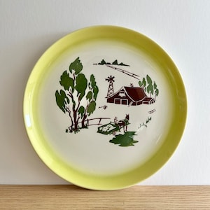 Peut inclure: Une assiette à dîner en céramique vintage jaune et blanche avec une scène de ferme brune et verte. La scène représente une grange, un moulin à vent, un chariot tiré par un cheval et des arbres.