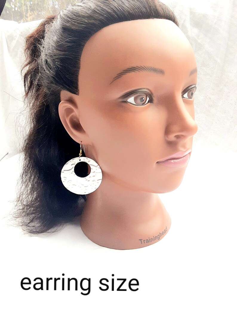 May include: Silver hammered circle earrings with a gold hook. The earrings are shown on a mannequin head.