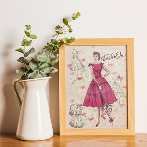 May include: A framed print of a vintage fashion illustration featuring a woman in a pink dress with a white polka dot umbrella. The illustration is surrounded by a floral pattern and the word "Fashion" is written in cursive at the top.