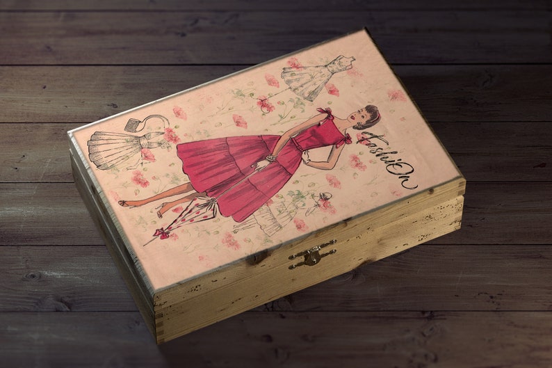 May include: A wooden box with a pink and white floral design featuring a woman in a red dress and the word "Fashion" on the lid.