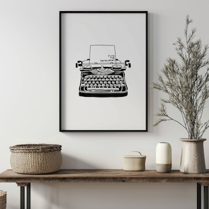 May include: Black and white framed print featuring a vintage typewriter illustration. The typewriter has a sheet of paper with the words "FUCK THE PATRIARCHY" printed on it. The print is displayed on a wooden bench.