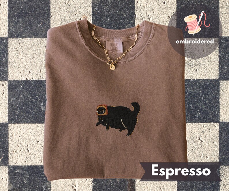 Puede incluir: Sudadera color espresso con un gato negro bordado con tostadas. Un collar de cadena dorada con un colgante descansa sobre la camisa. La palabra "embroidered" est&aacute; encima de la camisa. La palabra "Espresso" est&aacute; debajo.