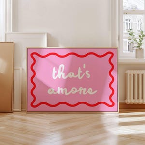 Puede incluir: Arte de pared enmarcado en rosa y rojo con el texto "that's amore" en blanco.
