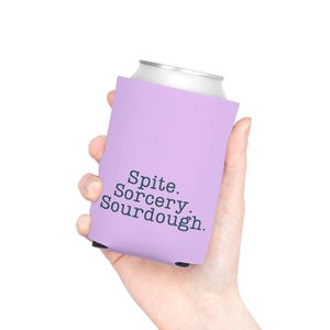 Can cooler featuring a dark serif font design that reads “Spite. Sorcery. Sourdough.” printed on a purple background.