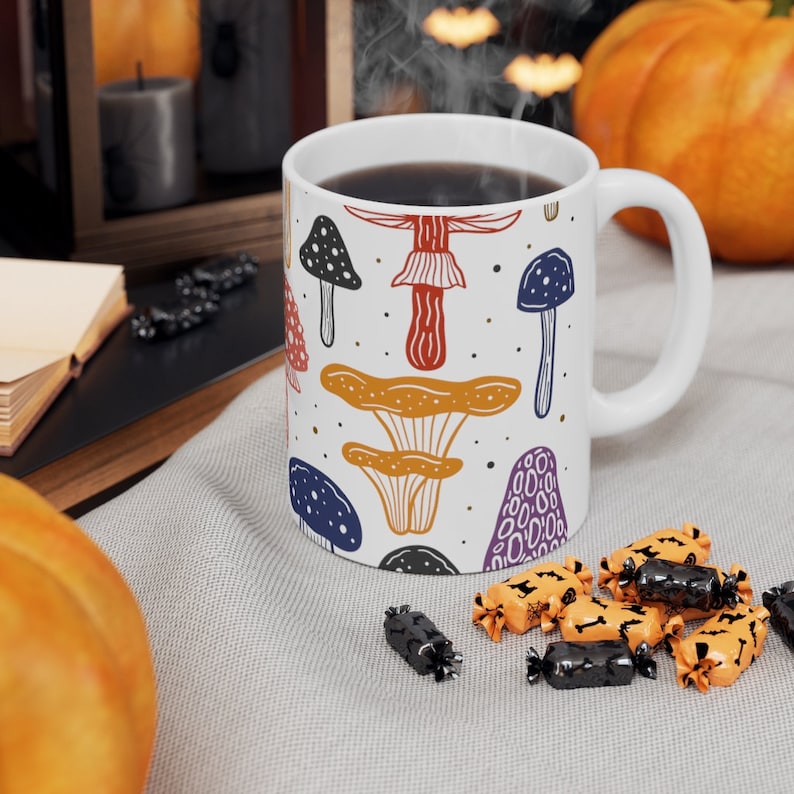 White ceramic mug featuring colorful illustrations of various mushrooms, perfect for mushroom enthusiasts and those who love nature-inspired designs.