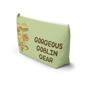 T-bottom pouch in moss green with a mushroom and the words Gorgeous Goblin Gear on the front and a cute snail with a positive message of You're doing great! on the back. Black zipper