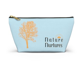 Può includere: Una pochette con cerniera blu chiaro con una cerniera nera. La pochette presenta una silhouette di un albero in arancione e il testo "la natura nutre" in nero.