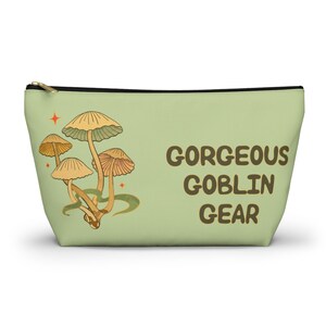 T-bottom pouch in moss green with a mushroom and the words Gorgeous Goblin Gear on the front and a cute snail with a positive message of You're doing great! on the back. Black zipper