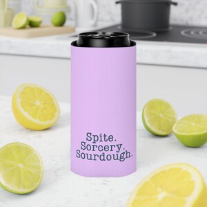 Can cooler featuring a dark serif font design that reads “Spite. Sorcery. Sourdough.” printed on a purple background.