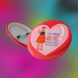 May include: Red heart-shaped button with a pin back. The button features an illustration of a woman in a black top and orange skirt, with the text "FAT THIGHS, RED EYES, CHUBBY GIRLS ARE GETTING HIGH."