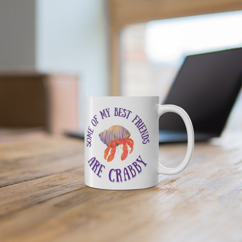 White ceramic mug featuring a cute hermit crab and the phrase “Some of My Best Friends Are Crabby” in a fun, beachy font.