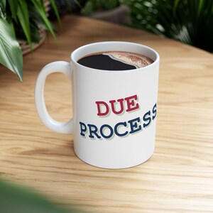 May include: White coffee mug with black coffee and the text "DUE PROCESS" in red, blue, and green letters.