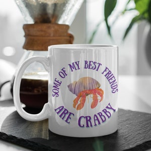 White ceramic mug featuring a cute hermit crab and the phrase “Some of My Best Friends Are Crabby” in a fun, beachy font.