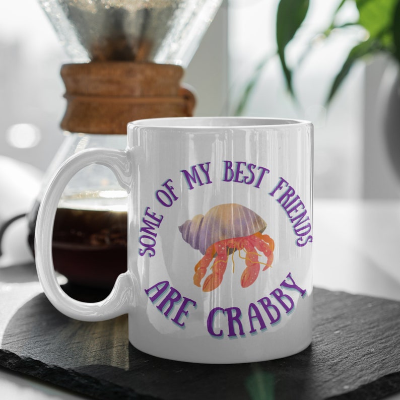 White ceramic mug featuring a cute hermit crab and the phrase “Some of My Best Friends Are Crabby” in a fun, beachy font.