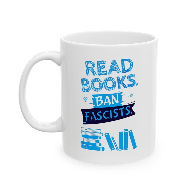 ceramic mug featuring bold blue hand-drawn text that reads "Read Books Ban Fascists" with illustrated books beneath the text.