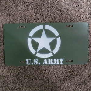May include: A green metal license plate with a white star and circle design and the text "U.S. ARMY" in white.