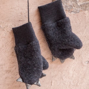 May include: A pair of gray fingerless mittens with black cuffs and silver-colored claws on the fingertips.