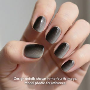 Może przedstawiać: Dłoń prezentująca manicure z efektem gradientu. Paznokcie przechodzą od ciemnego, przydymionego koloru u nasady do jaśniejszego, mieniącego się odcienia na końcach. Całość daje wyrafinowany, dopracowany wygląd.