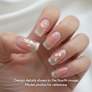 May include: Close-up of a hand with long, square-shaped nails. The nails feature a gradient design with a glittery silver tip and a clear base. Some nails have gold and white embellishments. The text at the bottom reads: Design details shown in the fourth image. Model photos for reference.