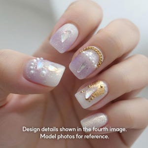 May include: Close-up of a hand with manicured nails. The nails feature a gradient design with white and lavender glitter. Some nails are adorned with pearls, gold chain, and gold leaf accents. Text on the image reads: Design details shown in the fourth image. Model photos for reference.