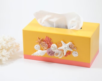 May include: Yellow tissue box cover with a pink trim and decorated with seashells, coral, and starfish.