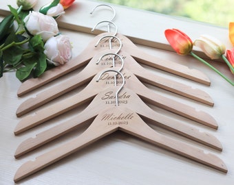 May include: Five wooden hangers with silver hooks, each personalized with a name and date. The names are "Alice", "Erin", "Danielle", "Sandra", and "Michelle".