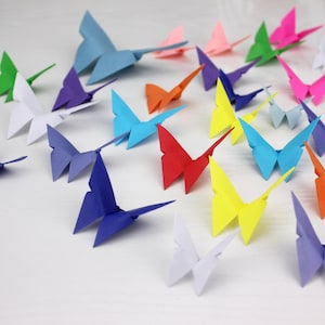 May include: A collection of colourful origami butterflies in various shades of blue, red, green, yellow, pink, and white. The butterflies are arranged on a white surface.
