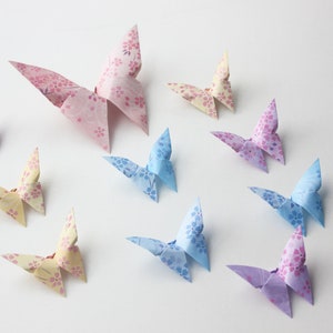 May include: A collection of ten origami butterflies in various pastel colors, including pink, blue, and yellow. Each butterfly has a floral pattern.