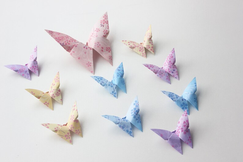 May include: A collection of ten origami butterflies in various pastel colors, including pink, blue, and yellow. Each butterfly has a floral pattern.