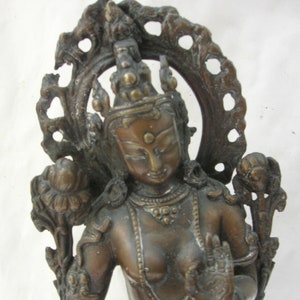 May include: A bronze statue of a seated deity with a halo and intricate details. The statue is in a meditative pose with one hand raised in a gesture of blessing.