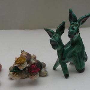 Puede incluir: Dos figuritas de burro de cerámica verde con un grupo de pequeñas figuritas coloridas a base de conchas.