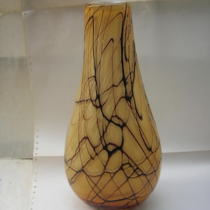 May include: A yellow glass vase with a brown and black abstract design.