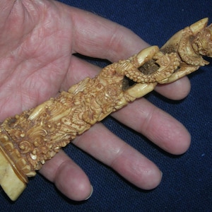 May include: A detailed ivory carving of a mythical creature with intricate details and a textured surface.