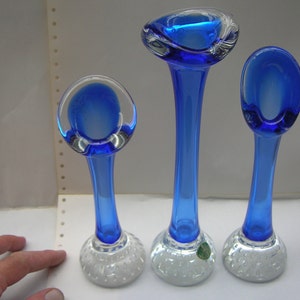 Könnte beinhalten: Set aus drei blauen Glas-Blumenvasen mit klaren Glasböden. Die Böden haben ein strukturiertes Blasendesign.