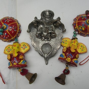 May include: An assortment of Indian-style decorative items. Includes two red and yellow elephant ornaments with bells, a silver metal deity, and two red, round, painted containers with string.