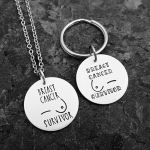 May include: Silver necklace and keychain with round pendants that say "Breast Cancer Survivor" with a stylized breast cancer ribbon symbol.