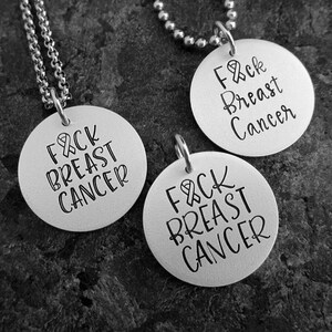 May include: Three silver necklaces with round pendants that say "F&CK BREAST CANCER".